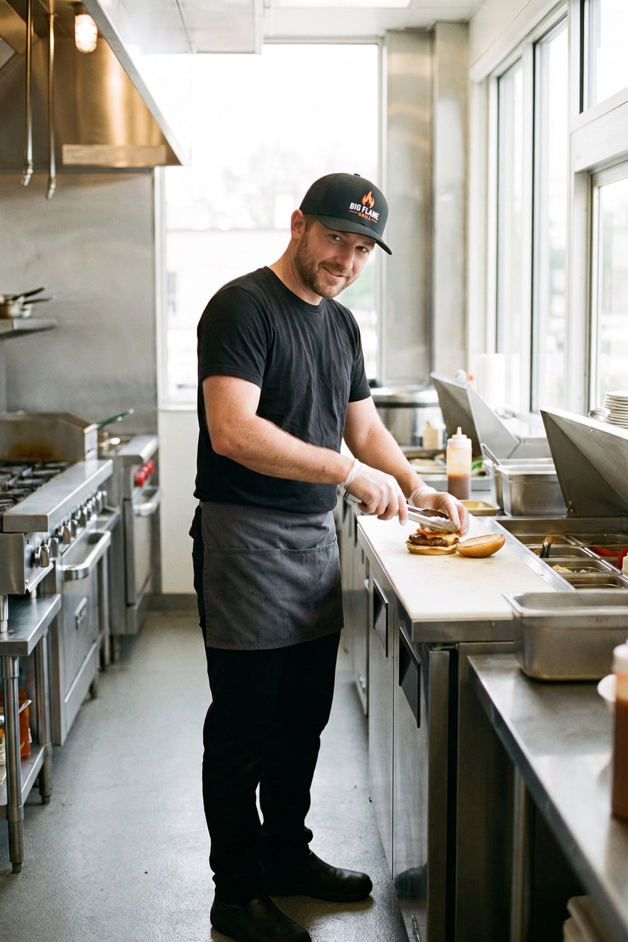 Restaurant cook in a custom embroidered black Richardson 112 cap with a flame logo