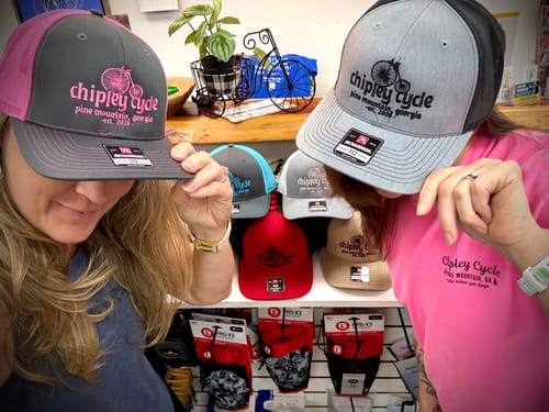 Two customers showing their embroidered trucker caps in a shop